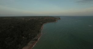 Aerial footage of beach with calm waters and vegetation close to the sea during sunset. Espelho beach, discovery coast, Bahia, Brazil