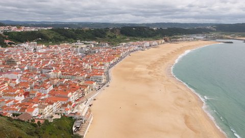 Historic Nazare town at the west coast of Portugal. Revealing shot of beautiful Nazare cityscape with an empty beach at Atlantic ocean in Portugal. Steadicam footage