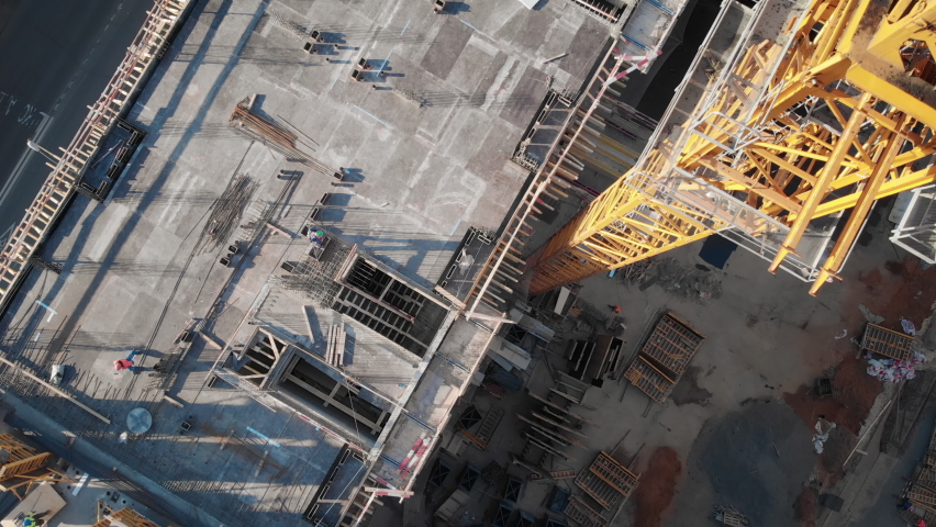 Top view to the construction works on the roof of a multi-storey building. Camera moves up along the giant crane showing all the construction site on the rooftop. Royalty-Free Stock Footage #1090117133