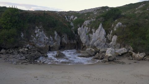Unique Gulpiyuri inland beach (flooded sinkhole) with sea coming from the cliffs in Cantabria, Spain, Europe