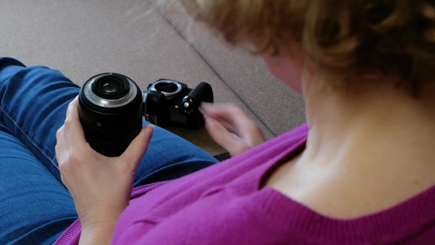 Beautiful photographer woman holding a digital camera citting in the sofa at home, indoors