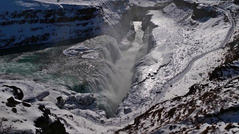 Stunning aerial view of the lower cascade of Gullfoss waterfall in southwestern Iceland, part of famous Golden Circle, in winter season with the canyon of Hvítá river, snow and ice-covered rocks.