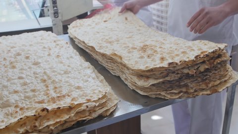 Armenian lavash production process at a bread bakery. Bakers put on the table and carry off many layers of hot toasted lavash for sale. Armenian cuisine. slow motion