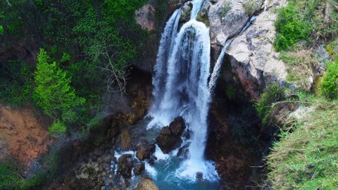 Beautiful large waterfall in a slow motion. Rocks, stones, green trees and bushes. Horizontal video. Waterfall in green forest, top view. Tropical in mountain jungle. 