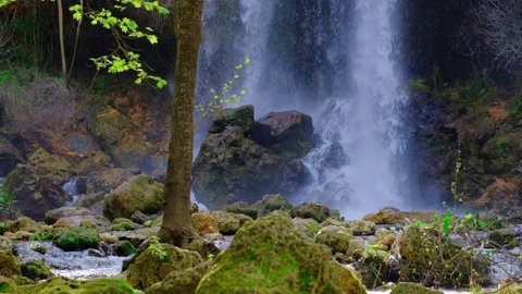 Beautiful large waterfall in a slow motion. Rocks, stones, green trees and bushes. Horizontal video. Waterfall in green forest. Tropical in mountain jungle. 