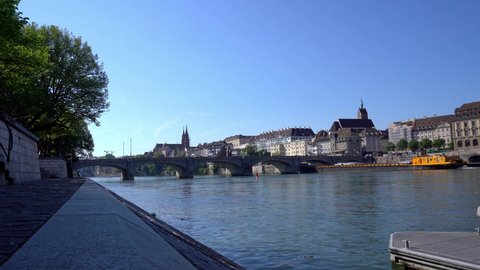 Yellow cargo ship named Aargau on Rhine River passing Middle Bridge at City of Basel on a sunny spring day. Movie shot May 11th, 2022, Basel, Switzerland.