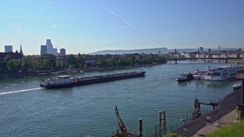 Cargo ship named Aquitaine on Rhine River at City of Basel on a sunny spring day. Movie shot May 11th, 2022, Basel, Switzerland.