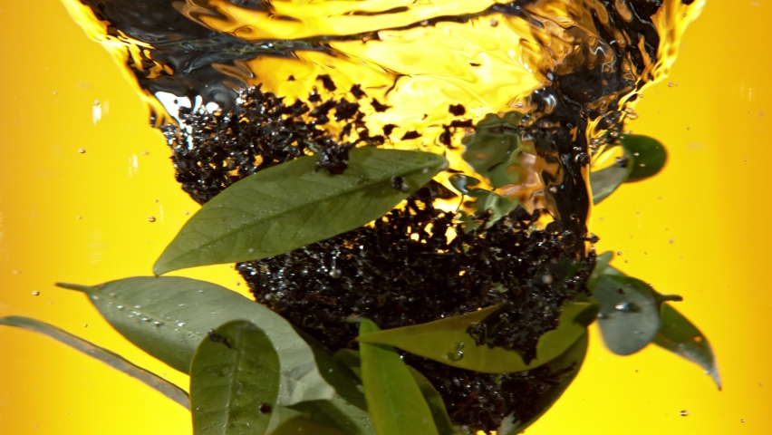 Super slow motion of pouring black tea into water in twister shape. Fresh green leaves mixing with dry tea. Filmed on high speed cinema camera, 1000fps. Speed ramp effect. Royalty-Free Stock Footage #1090126239