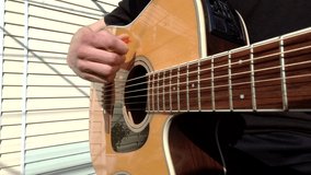 4k 60 fps guitar playing video. A man plays an acoustic guitar outdoor. Strings waves close-up. Musician is playing music on acoustic guitar with fingers. 