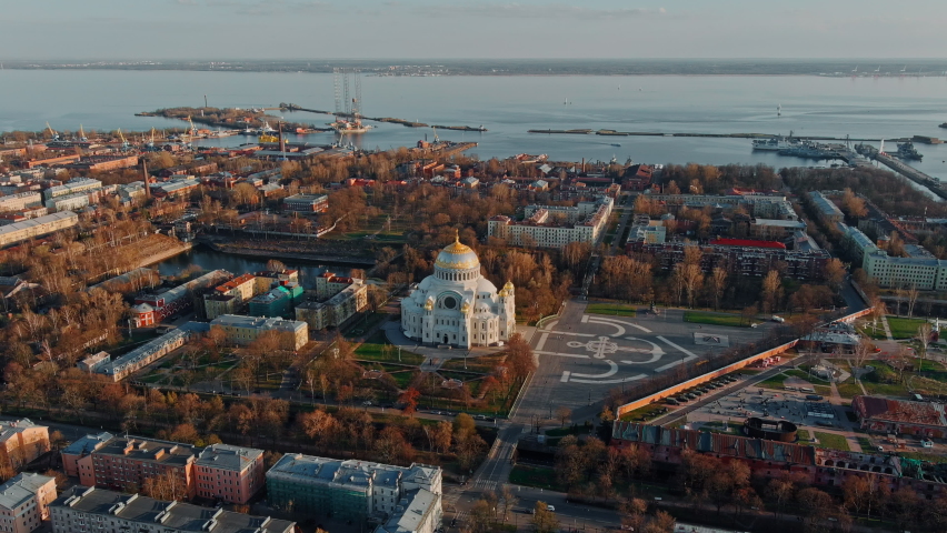 Aerial view of the sea capital of Russia Kronstadt at sunset, the golden dome of the huge main naval cathedral of St. Nicholas, the seaport with warships, dry docks, fortifications with cranes