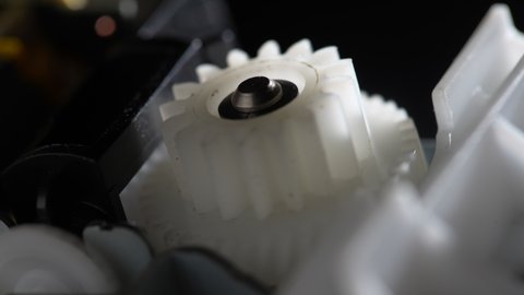 Gears rotating in a mechanical device. Machine white plastic gears rotating abstract. Cog wheels machinery, close up, macro