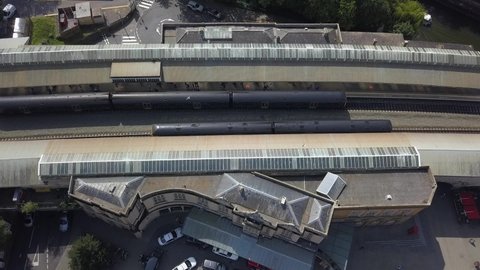 Aerial view of trains at the station in sunny Bath, England, UK - pull back, drone shot