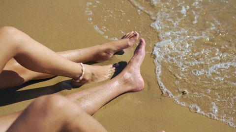 Feet of a young couple of men and women lying on a tropical sandy beach near Ocean. Male and female legs sunbathe and relax on the exotic resort. Romantic vacation for couple in love.4K