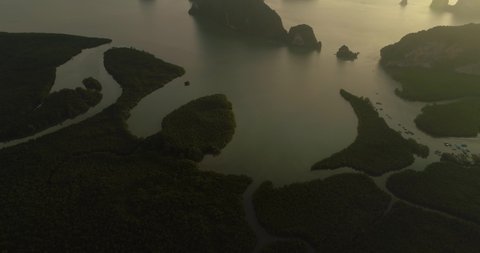 Phang Nga bay with multiple islands during hazy golden hour sunrise, establishing shot, aerial
