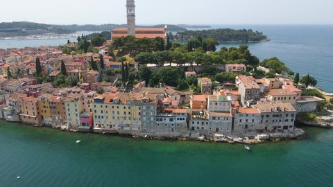 Aerial rotating shot of St. Euphemia church surrounded by medieval old town in Rovinj, Istria, Croatia on a bright sunny day.
