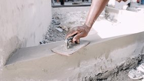 Unrecognizable worker levels fresh concrete with spatula. Slow motion