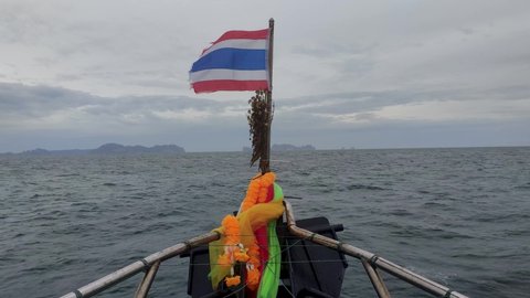 Flag of Thailand on a cruise boat waving on the ocean with beautiful islands in the background