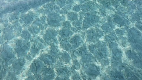Abstract blue water surface from the pool reflects the sunlight.