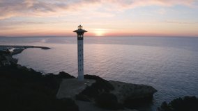 Aerial shot passing by a lighthouse towards the sea at dawn