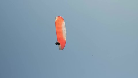 Parachutes or paragliding experience. Adrenaline and extreme sport. Extreme paraglider flying in sky at sunny day. People paragliding. Person paragliding over seashore. Sport activity concept