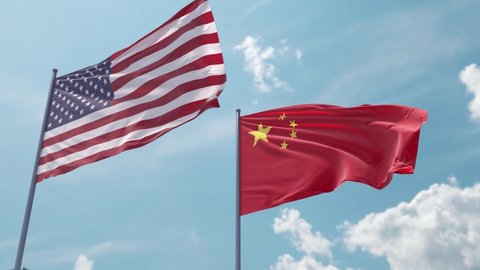 Flag of the USA and China on the flagpole flutters quickly with a strong wind in the blue sky