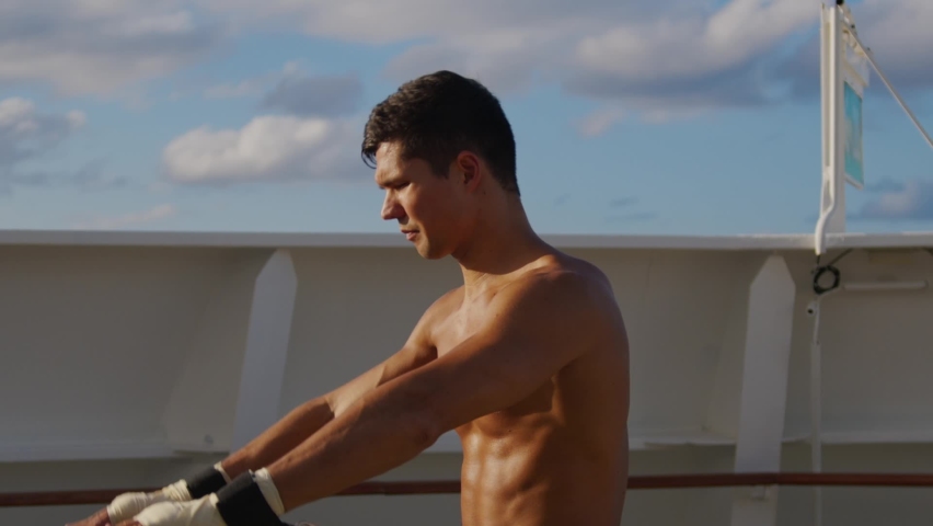 Young handsome man stretches body with resistance band training strap system