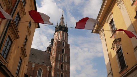 Famous Saint Mary's Basilica (Mariacki Church Kraków) at the Main Market Square in the Old Town district of Krakow, Poland. Seen from the Floriańska street, with Polish flags hanged above.