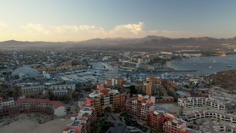 Drone shot of resorts on Playa El Médano with mountains in the distance in Cabo San Lucas Mexico, wide and rotating