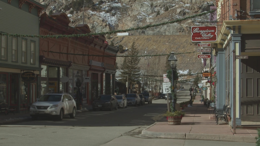 Static view of houses with shops on both sides of the road in western state of Utah with high mountains in background in United States.