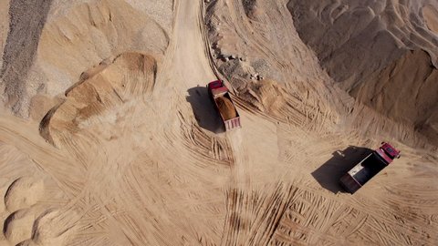 Sand transport from open pit. Dump truck transports sand and gravel in open-pit mine, drone view. Bulk Transport for construction. Earthmoving in quarry. Lorry in opencast. Mining industry concept.