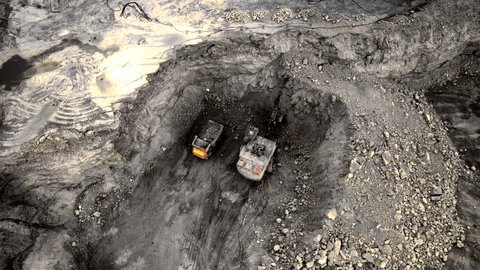 Excavator loads ore in haul truck in quarry. Excavator digging in open pit gold mine. Mining truck hauling iron ore from copper open-pit. Coal mining in open pit. Overburden removal in opencast. 