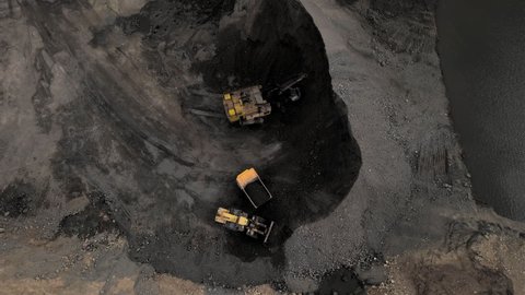 Coal mining in an open pit. Mining excavator loads coal in haul truck in quarry. Excavator digging in an open pit coal mine. Tipper truck hauling minerals from open-pit. Heavy machinery in opencast. 