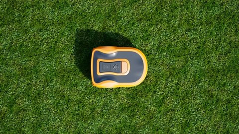 A lawn robot mows the yard. Robotic lawnmower trimming the grass. House yard auto lawn mower cutting grass. Wireless controlled smart equipment for garden grass mow. Modern remote technology.