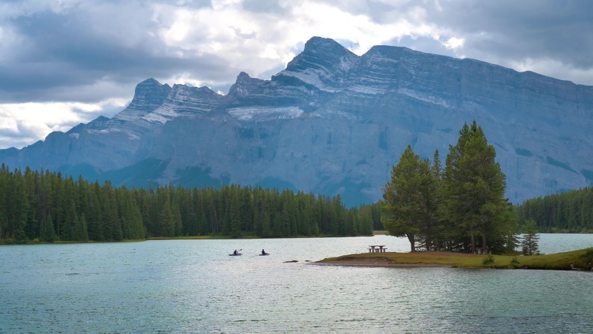 Two canoes with paddling tourists floating on Two Jack Lake with Mt. Rundle in the background in Banff National Park, Alberta, Canada. 4K UHD video.