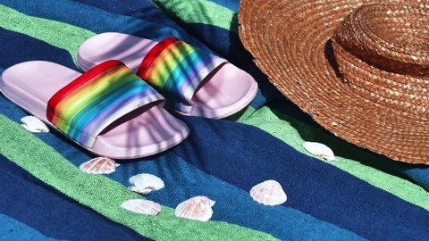 Colored flip flops and shells with hat on towel