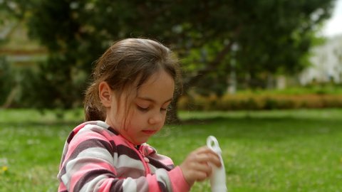 Cute little girl blowing soap bubbles in nature. Close-up. Cute baby girl blowing soap bubbles at the camera and having fun. Little cute girl is playing outside blowing soap bubbles.