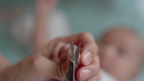 Mother cutting baby's nails. Closeup view