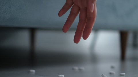 defocus hand scatters pills on the floor. passed out female suffering depression lying unconscious on bed at home after having pills overdose intoxicated by mix of antidepressant.