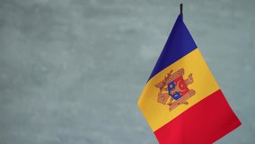 State flag of Republic of Moldova waving on gray background. Moldavian flag and place for text