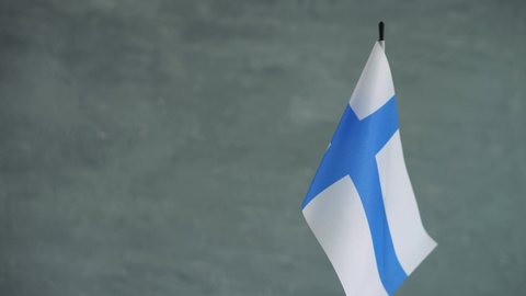 State flag of Republic of Finland waving on gray background. Finnish flag and place for text