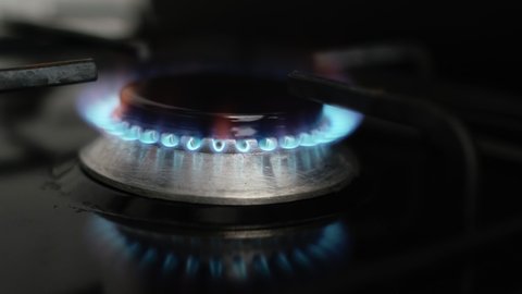 Close Up of Turning On Stove Gas in Kitchen or Home. Lighting Kitchen Burner of Gas Stove Indoors. Stove Burner Igniting into Blue Cooking Flame. Natural gas inflammation in Slow Motion. 