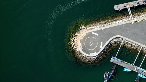 Downwards spirral towards helicopter helipad next to boats on water