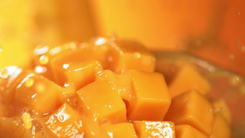 Slow Motion Shot of Mango Juice Splashing through Mango Cube Slices
