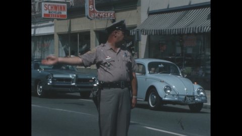 Decade 1950s: Traffic cop directs traffic in middle of small town street.