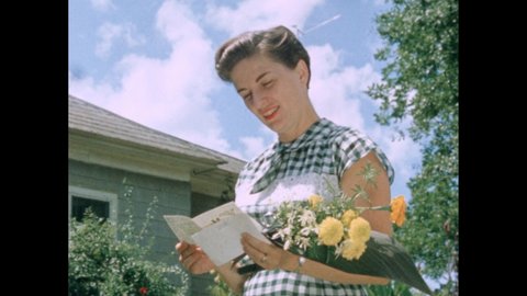 1950s: Woman holding flower bouquet, reading card, talking. Hand holding clapperboard. People standing outside reading greeting card, talking.