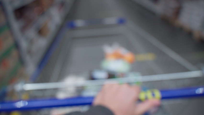 A shopping basket in hand in a grocery hypermarket. Selective focus. Blurr, defocusing