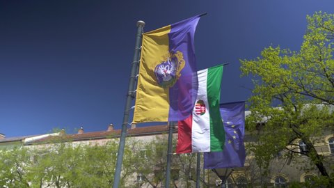 Flags waving in the wind. The Hungarian city flag of Szolnok, the Hungarian flag and the EU flag can be seen.