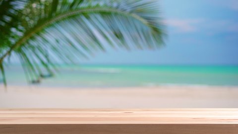 Empty plank wooden table with palm leaf and beautiful tropical white sand beach background, Summer vacation concept