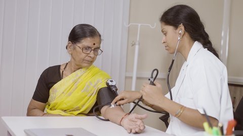 Doctor checking blood pressure or bp of senior woman patient at hospital - concept of health care, medical treatment and consultation.