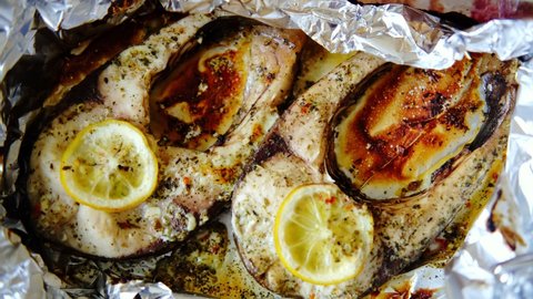 Baked fish silver carp steaks. Pieces of fish cooked in the oven in foil with lemon and spices.